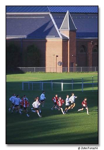 Men's soccer team running sprints in late afternoon light. Andrus Field and the Alumni Athletic Building, Wesleyan University, Middletown, Connecticut. September 2000.