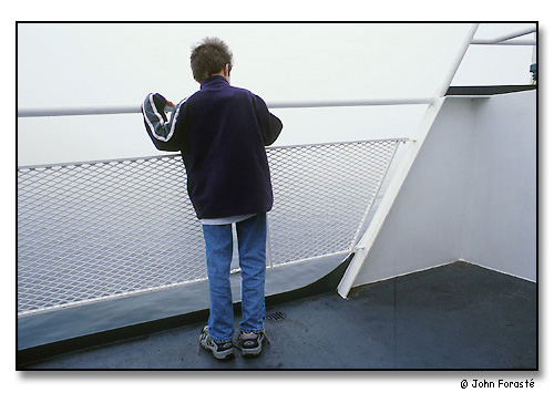 Boy on top deck of the Block Island Ferry on a foggy and windy day. <br> En route from Point Judith to Block Island, Rhode Island Sound/Atlantic Ocean. September 2000.