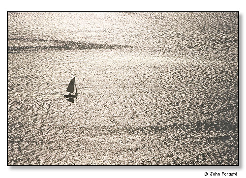 Sailboat and sun on water.