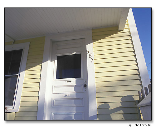 Detail of sunlight, door & yellow clapboards. <br>Provincetown (Cape Cod), Massachusetts. April 2001.