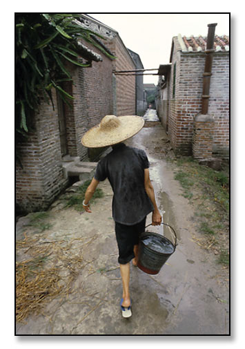 Woman carrying bucket of water. China. July 1979.